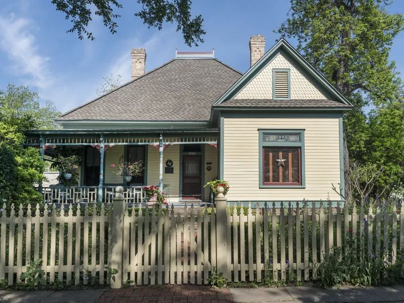 A Victorian cottage behind a white picket fence in Austin's Hyde Park neighborhood